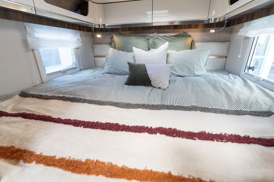 4-berth campervan rear double bed with striped bedding and side windows