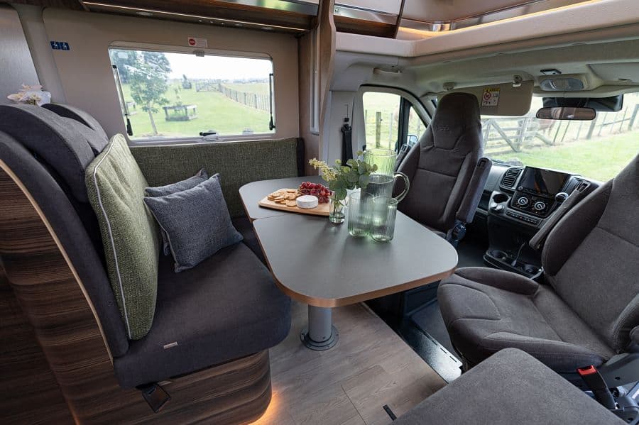 4-berth campervan dining area with cheese board and meadow view through window