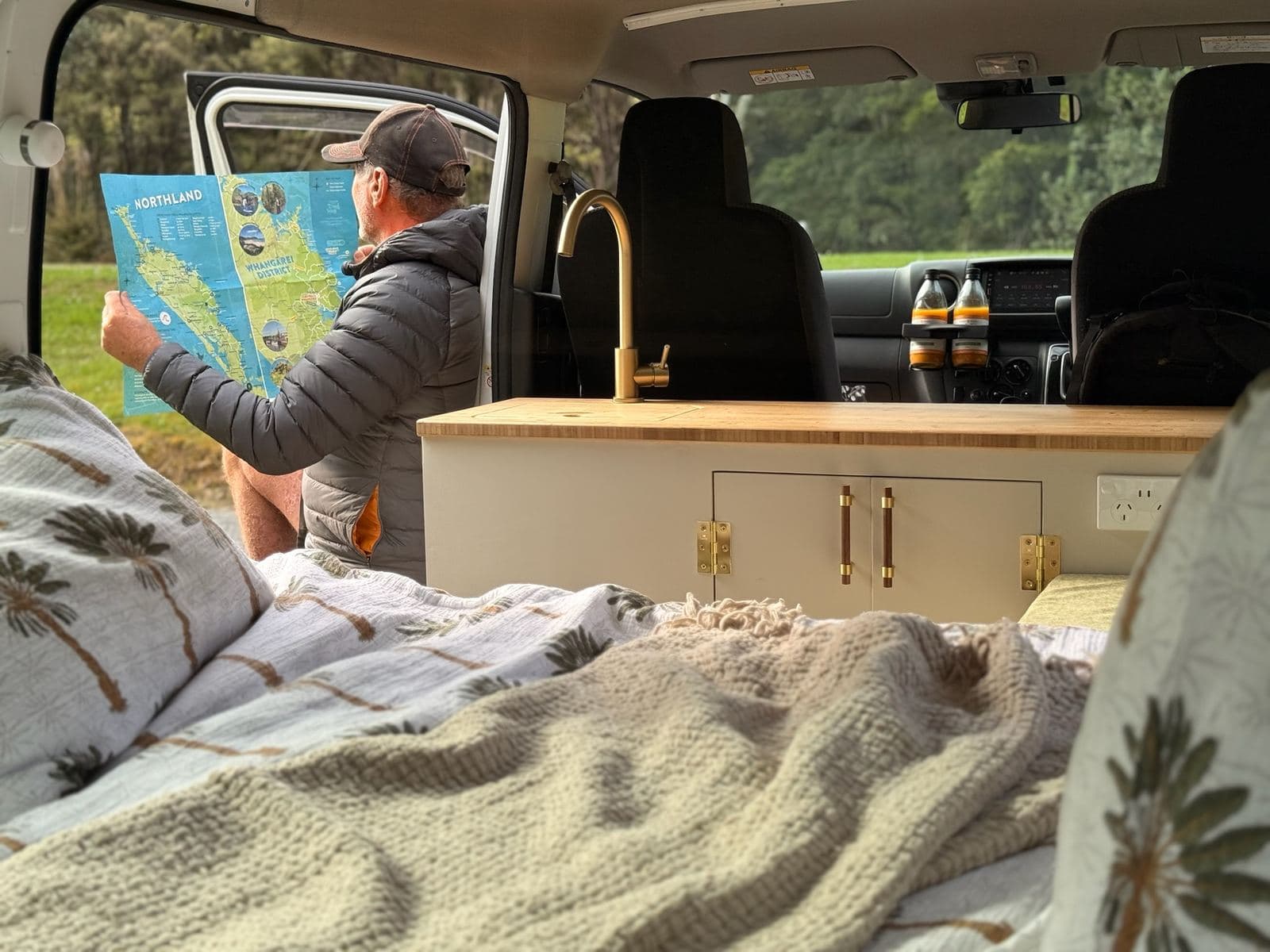 Inside the Pīwakawaka: bamboo worktop, brass tap, sink and a 230V socket, with the cab beyond