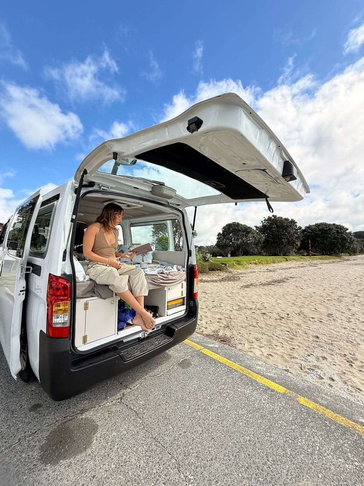 The Pīwakawaka parked beside a beach with the tailgate up and the bed made