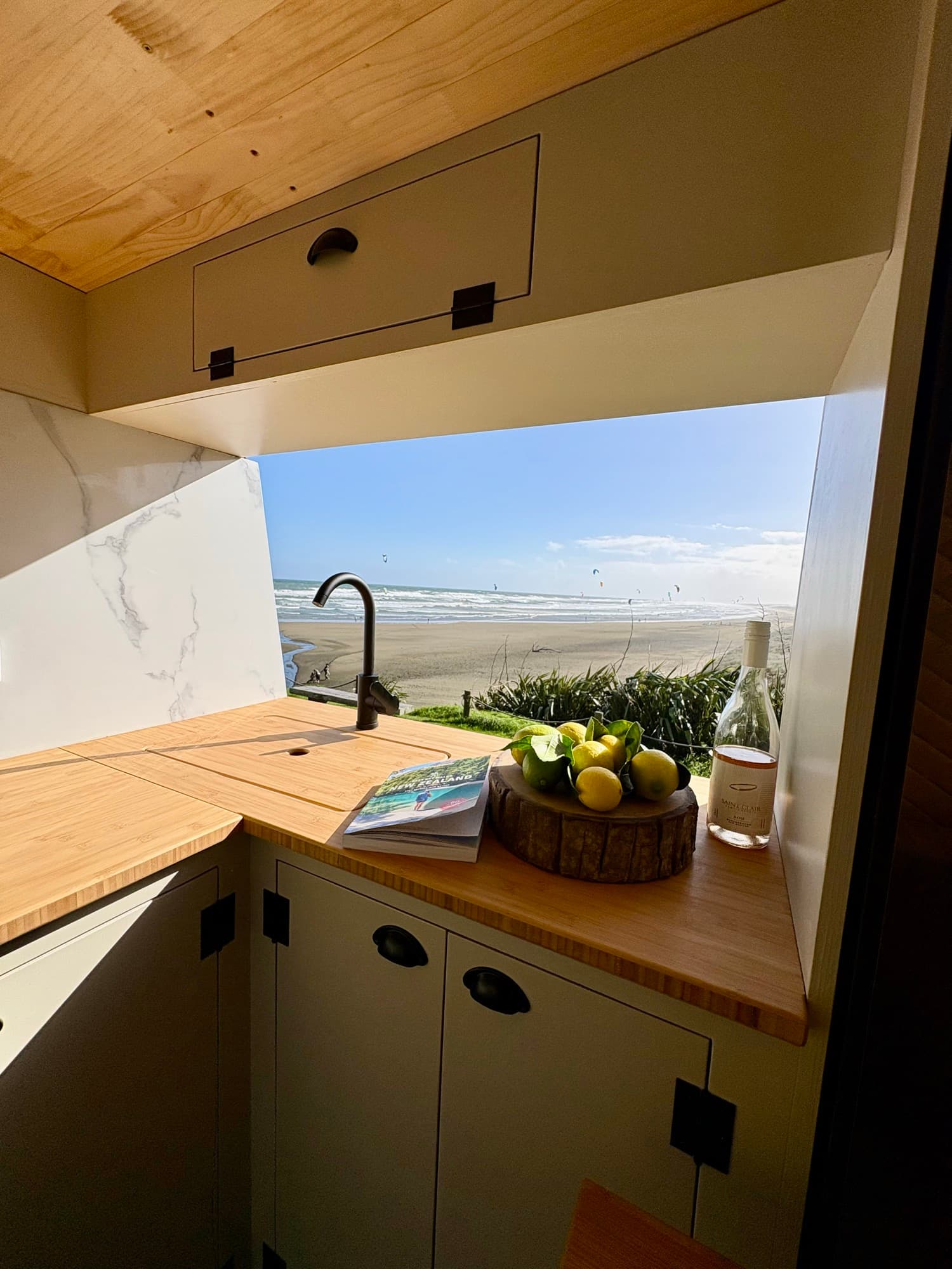 Tūī 2-berth campervan galley kitchen with sink, fruit bowl and ocean view