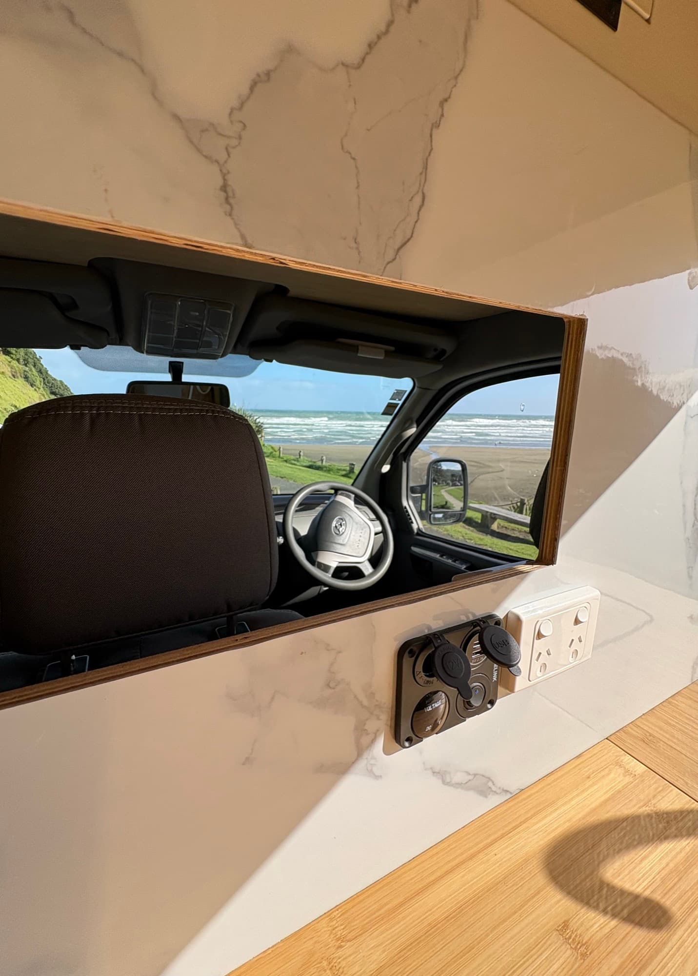 Tūī 2-berth campervan power points and marble splashback with a view through to the cab and beach
