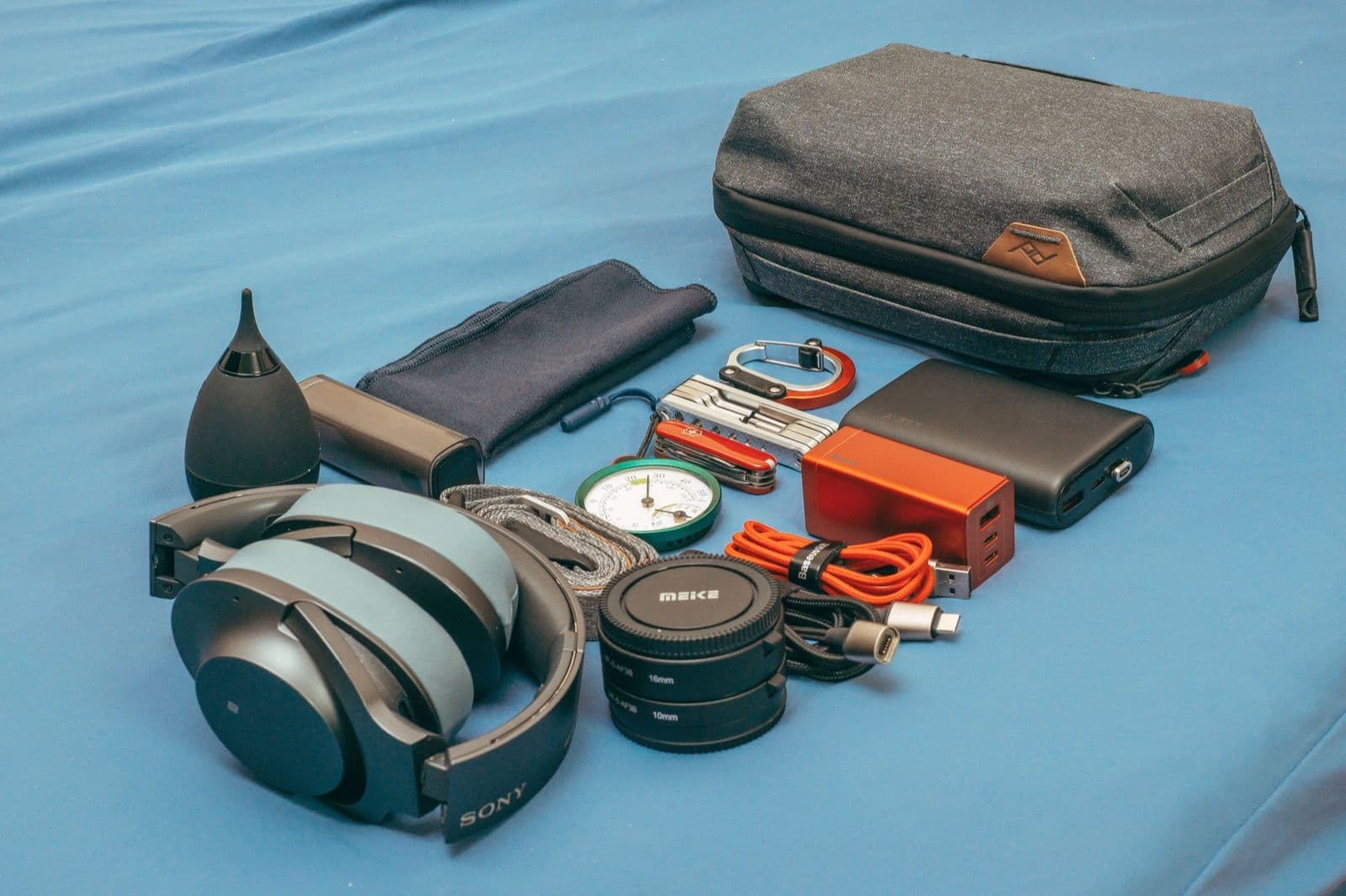 Travel gear laid out including a power bank, adapter and headphones for a New Zealand road trip