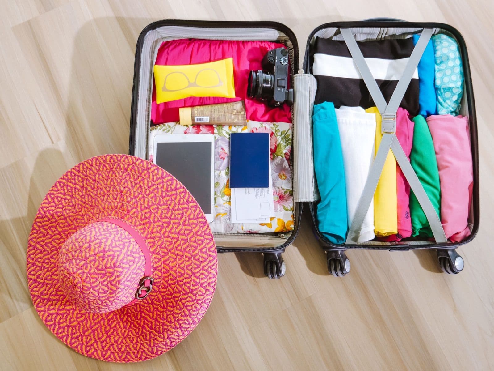 Open case packed with folded clothes and a sun hat, ready for a New Zealand campervan trip