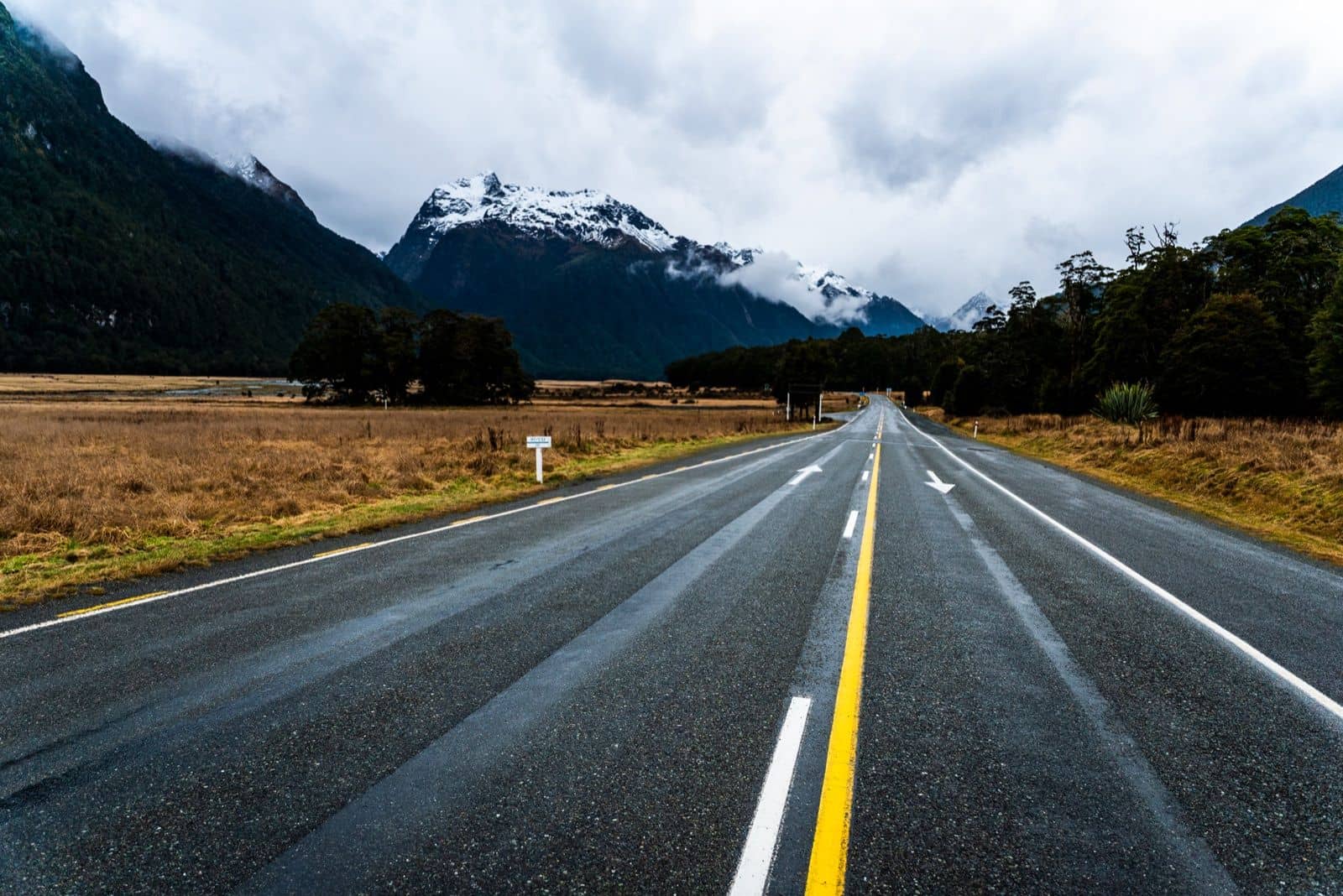 Mountain road in New Zealand with snow-capped peaks, typical driving conditions for a campervan