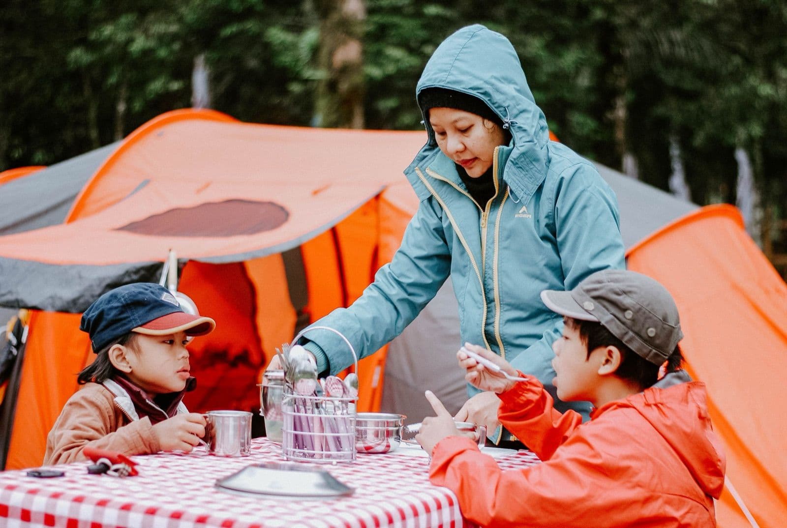 Parent and two children eating at a table outside on a family camping trip