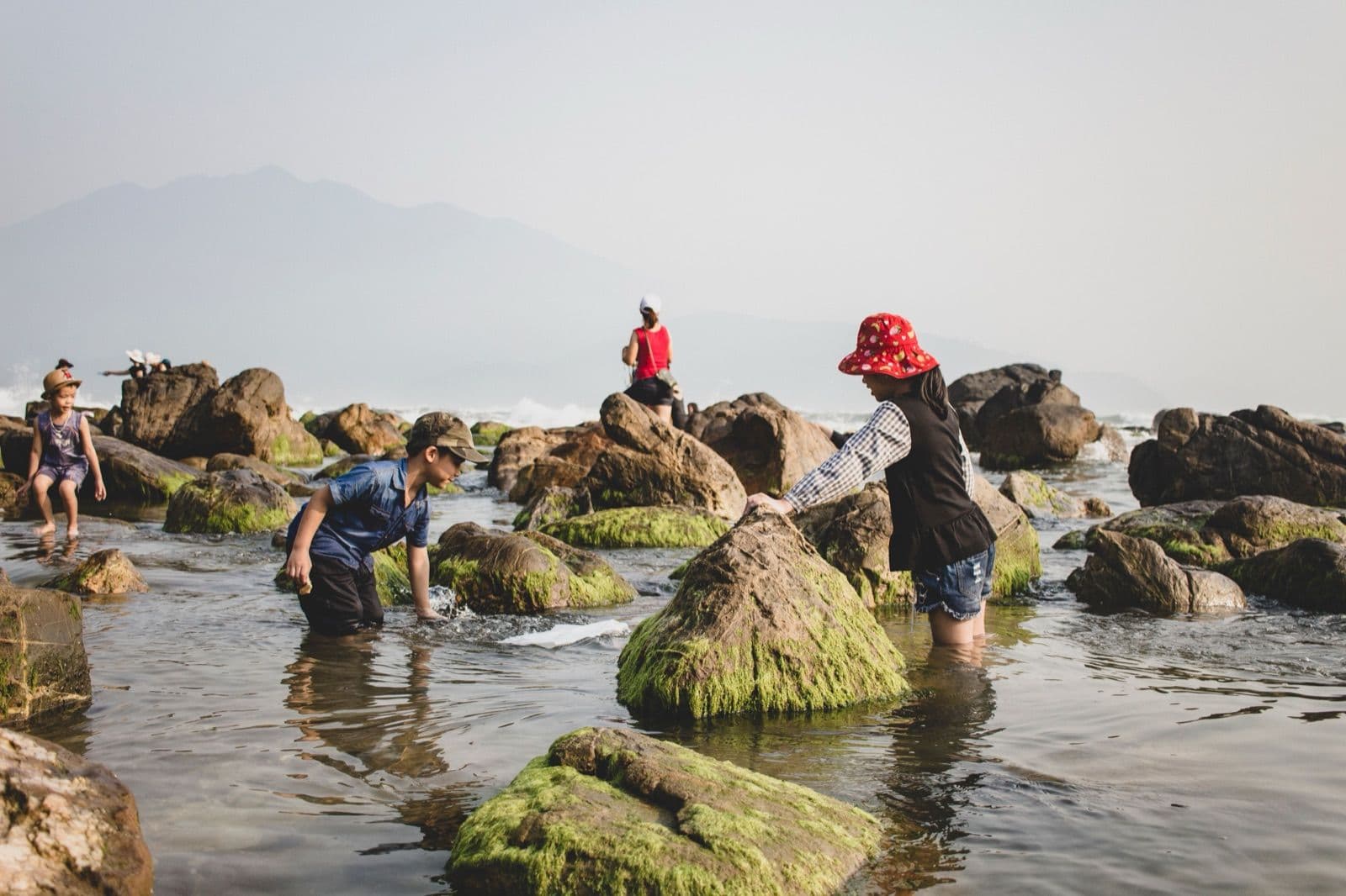 Children exploring rock pools on a shoreline, the kind of unplanned stop a campervan trip with kids makes possible