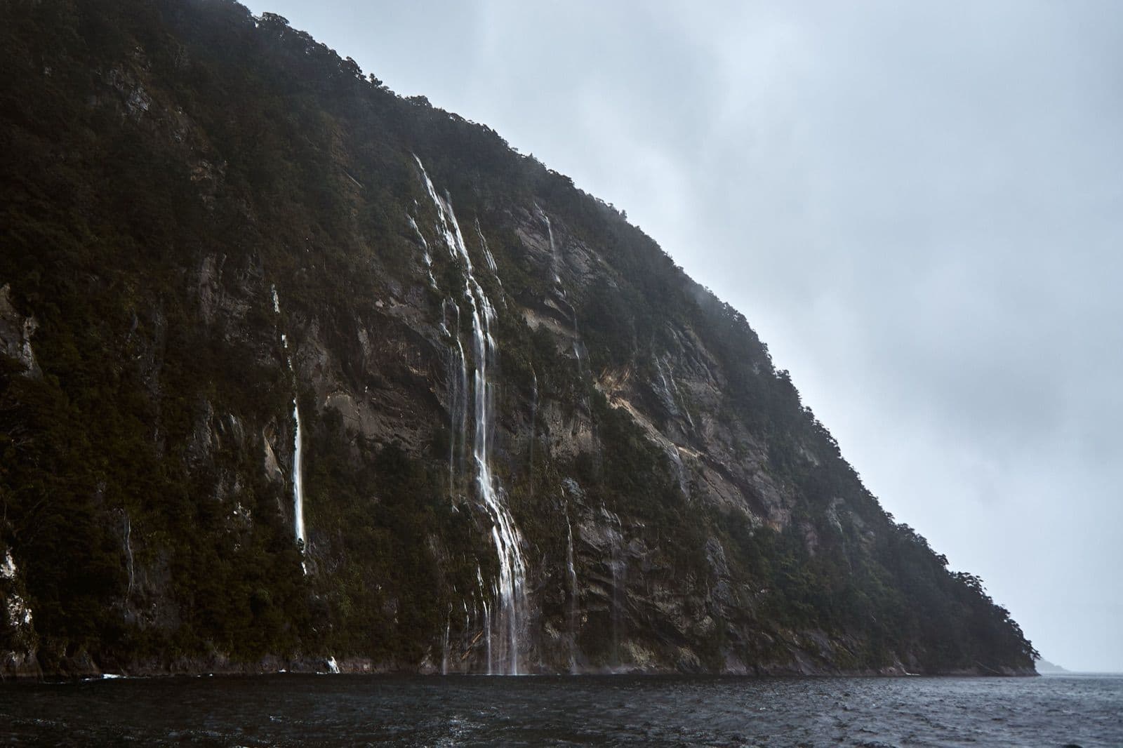 Wasserfälle stürzen eine steile Felswand hinab im Milford Sound