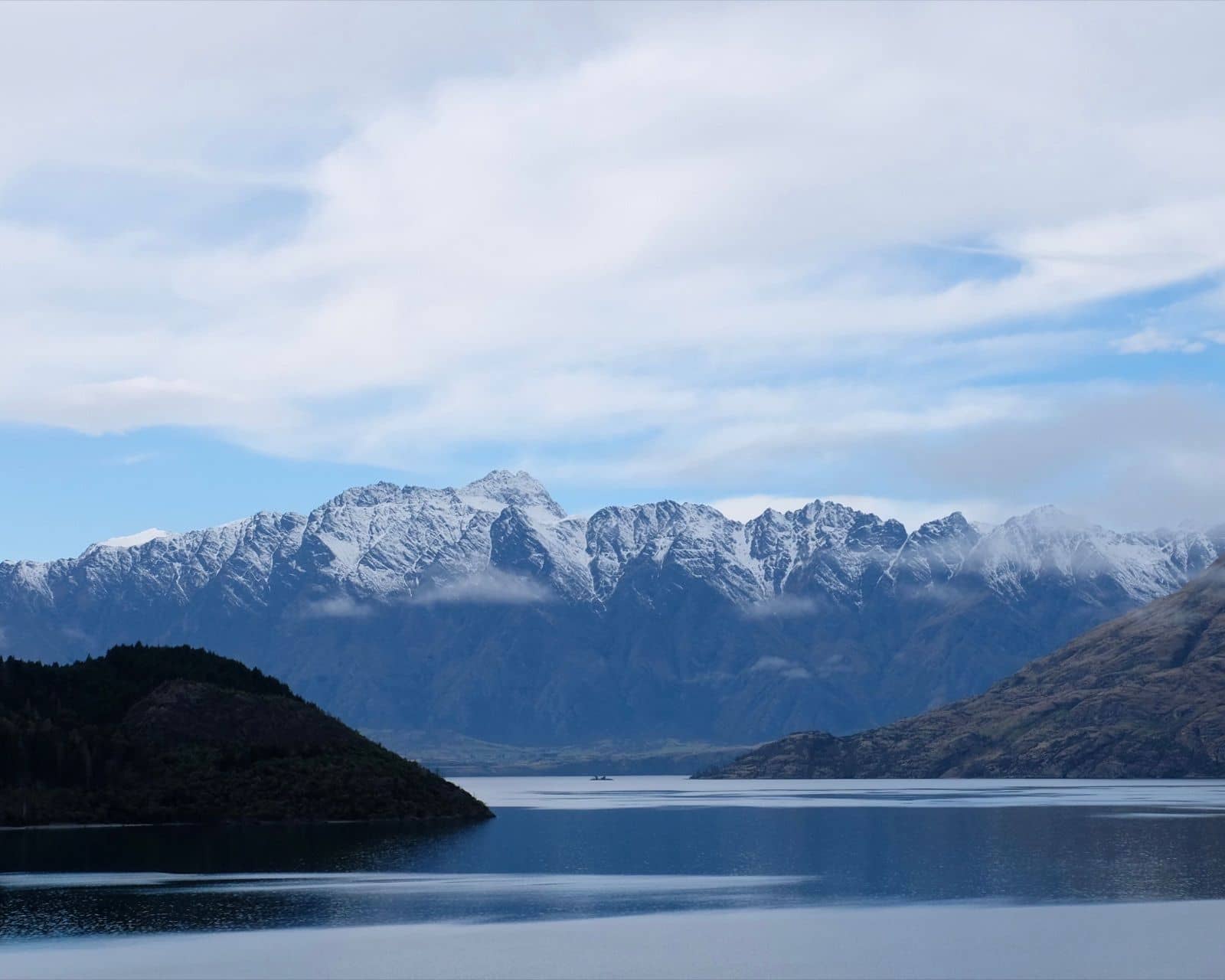 Schneebedeckte Berge über einem ruhigen See auf einer Neuseeland-Rundreise