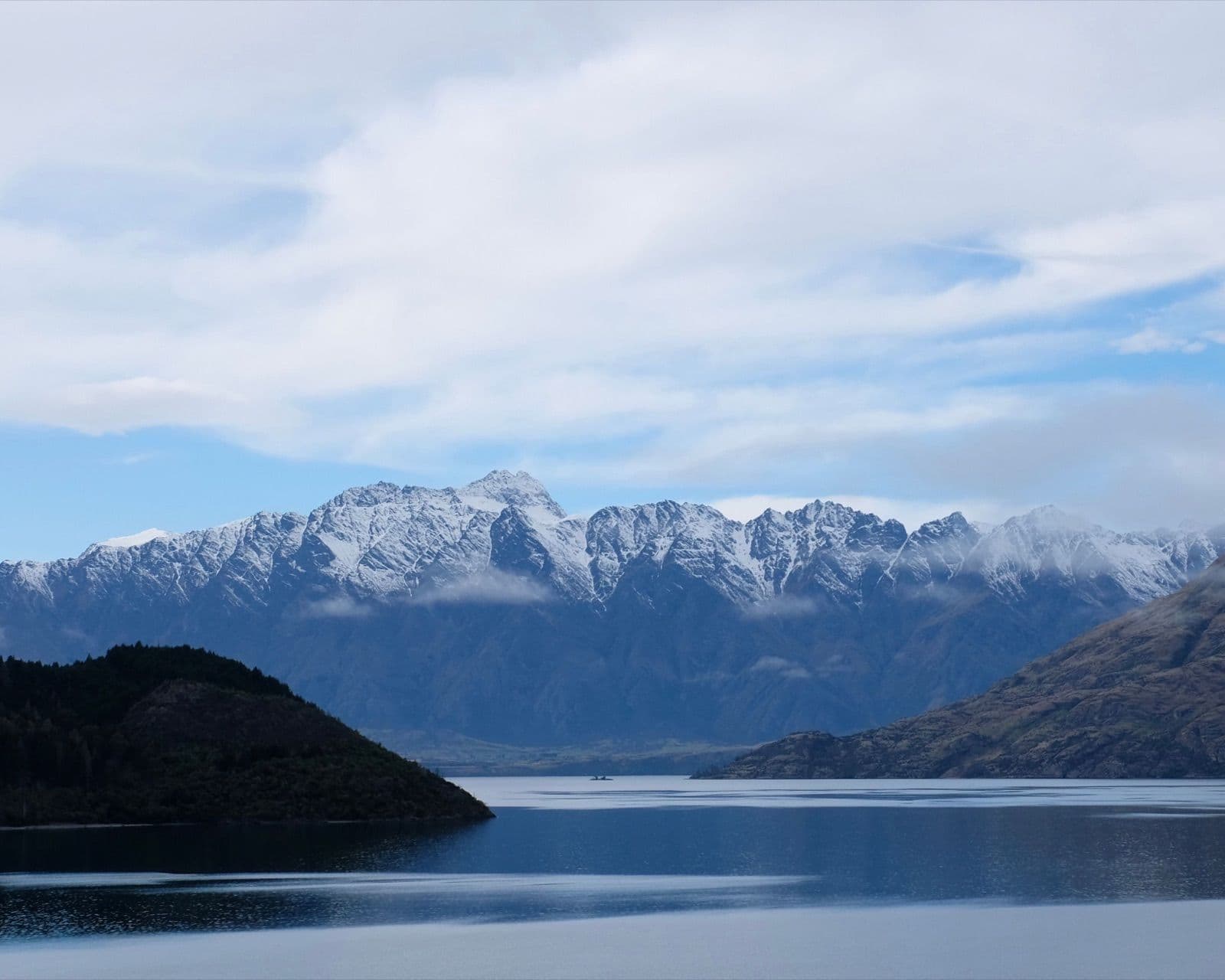 Schneebedeckte Berge über einem ruhigen See auf einer Neuseeland-Rundreise