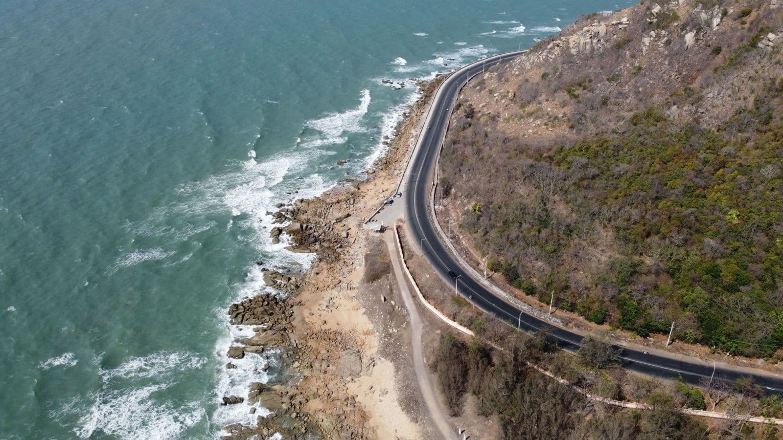 Kronkelende kustweg langs rotsachtige kliffen in Nieuw-Zeeland