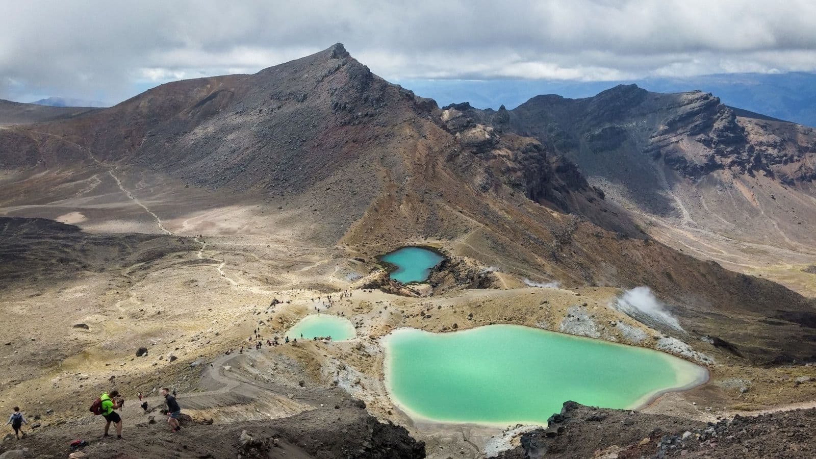 De Emerald Lakes op de Tongariro Alpine Crossing, drie groenblauwe kratermeren met stoom en wandelaars op het pad