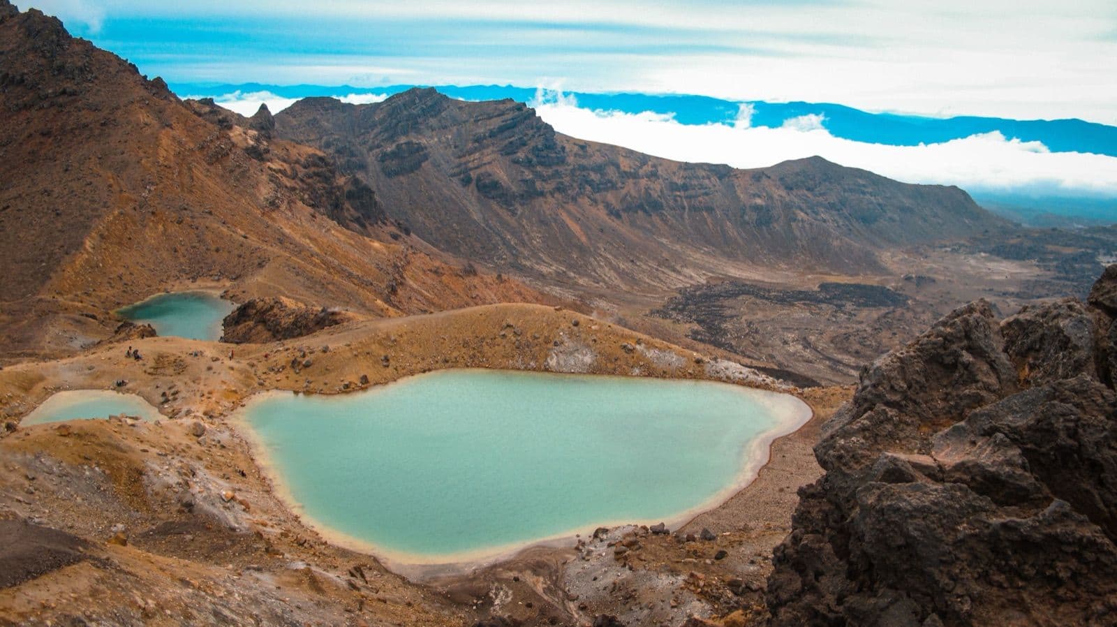 A crater lake and bare volcanic terrain on the Tongariro Alpine Crossing hiking route in New Zealand